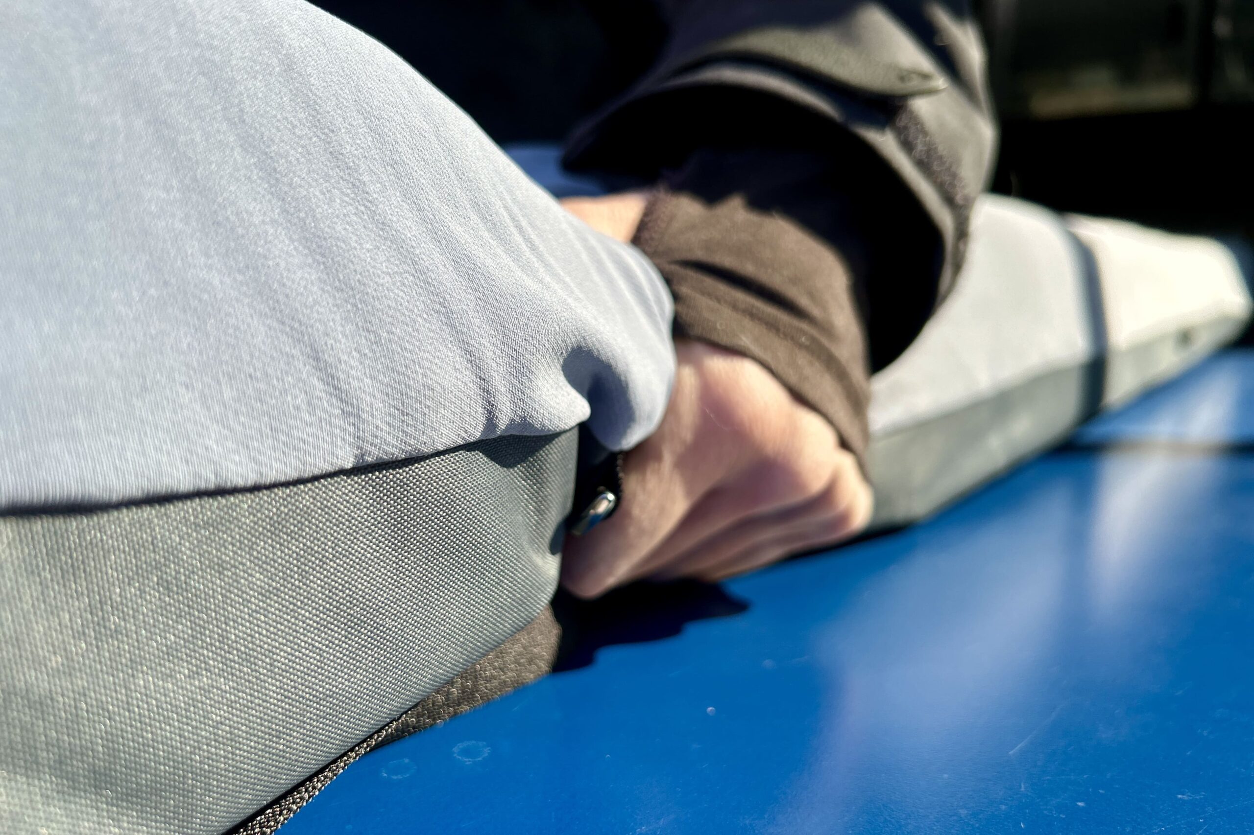 A person's hand grasps the side of a camping mattress.