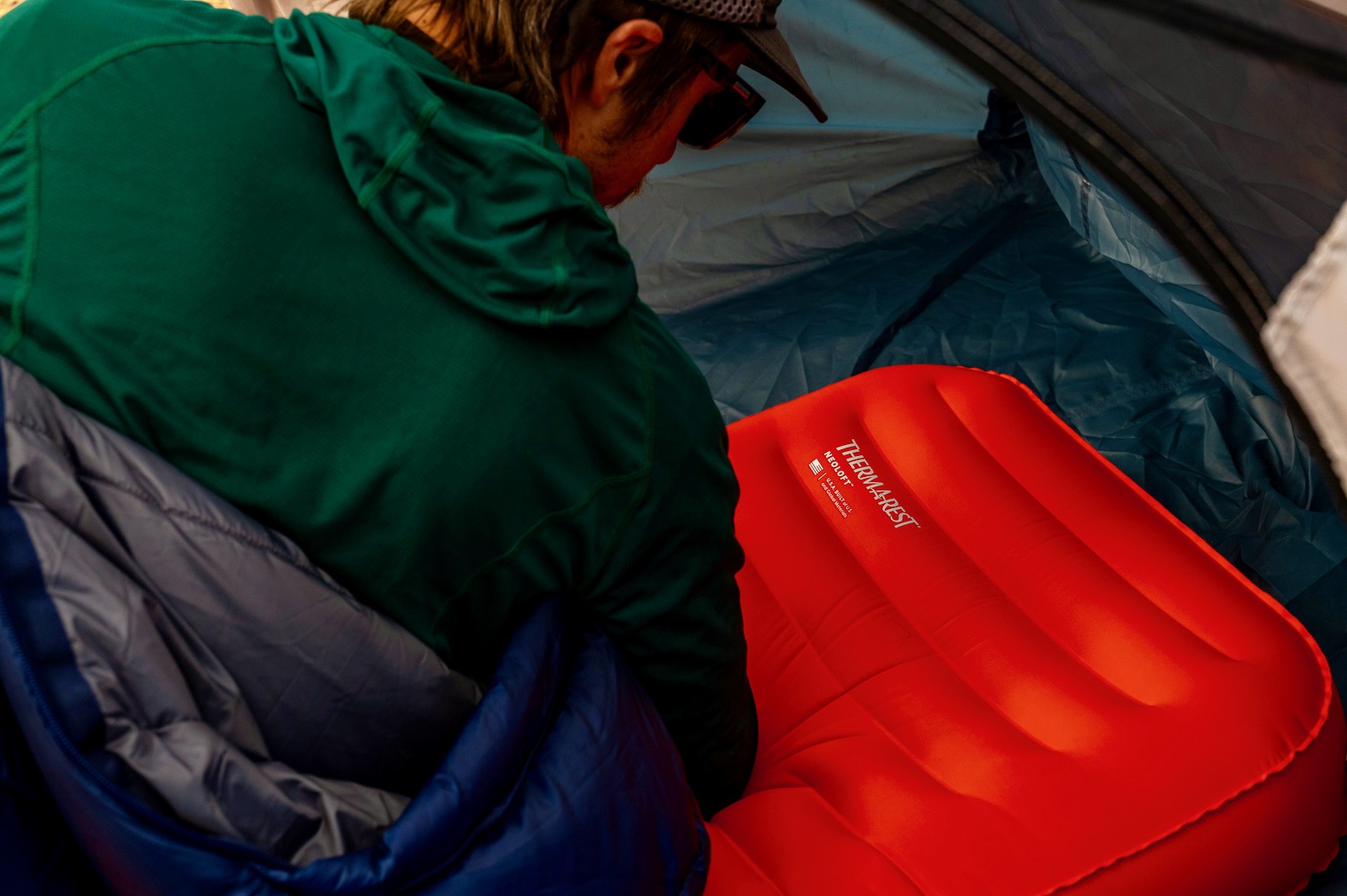 a hiker lays on a sleeping pad and looks at the logo