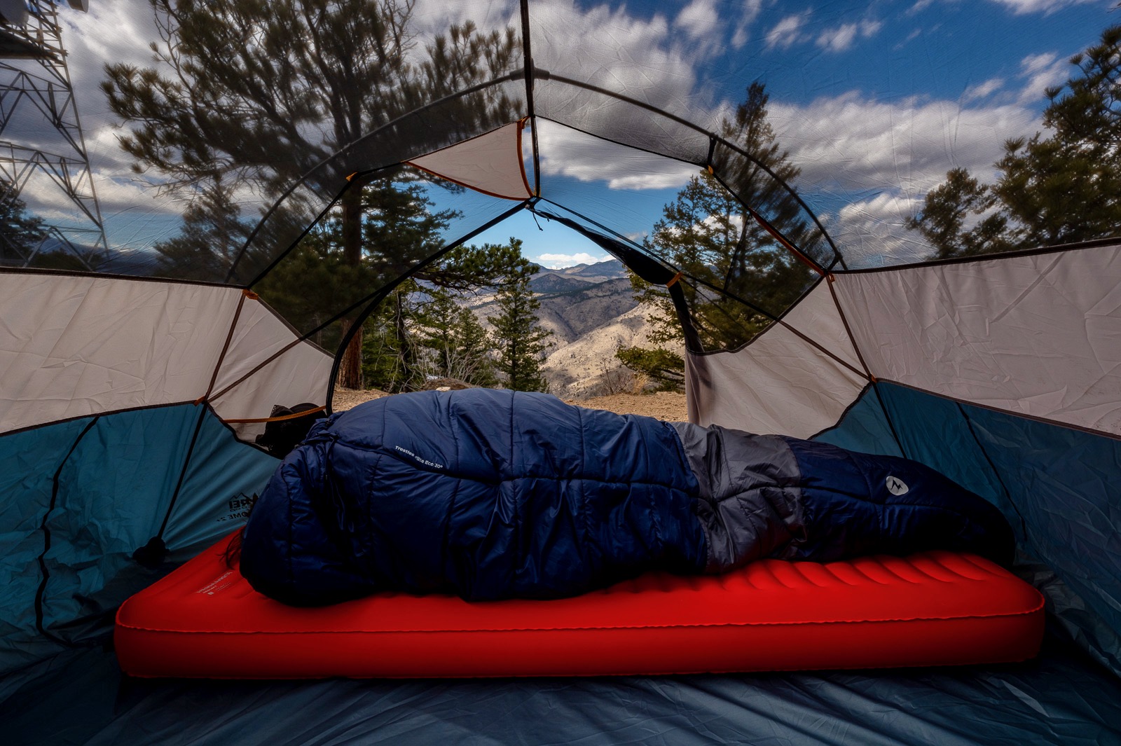 a hiker lays in a sleeping bag on a sleeping pad in a tent