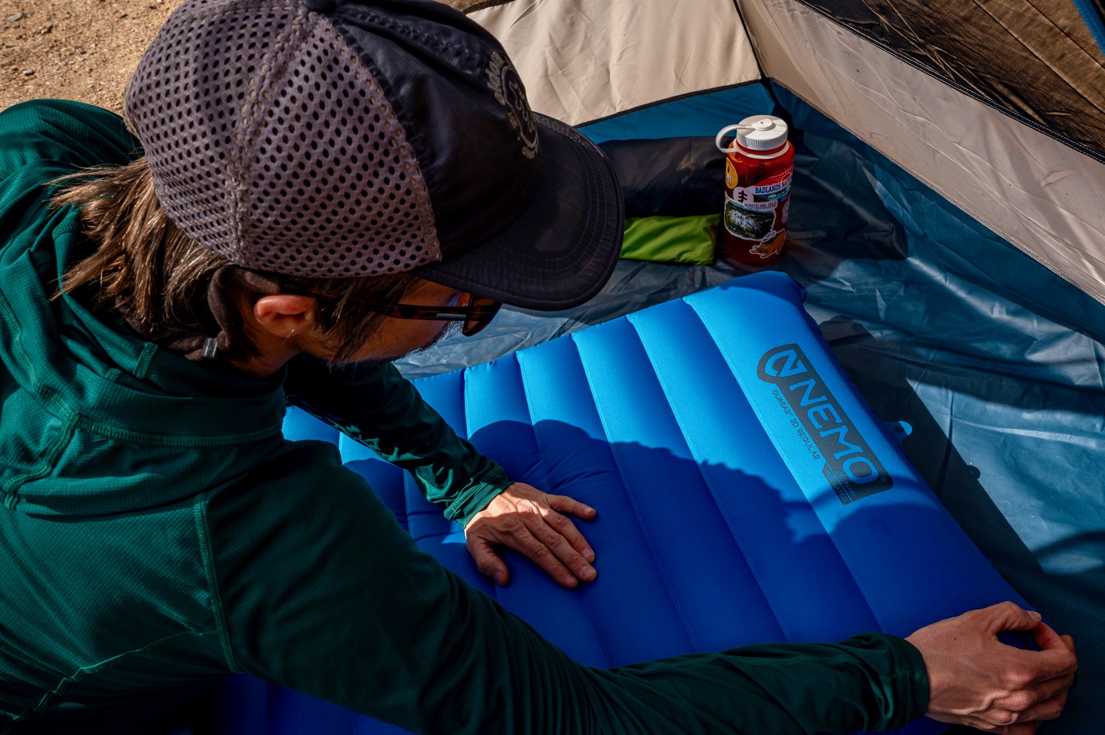 a hiker leans on a blue sleeping pad in a tent