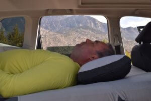 A male hiker rests in his vehicle on an inflatable mattress made to fit his vehicle