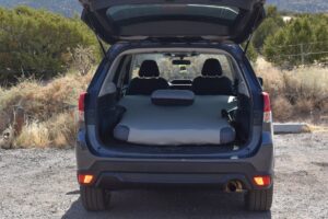 Rear view of a vehicle's hatchback raised up to show a custom vehicle mattress with a matching camp pillow.