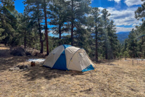 A side view of a tent with blue skys and mountains in the background.