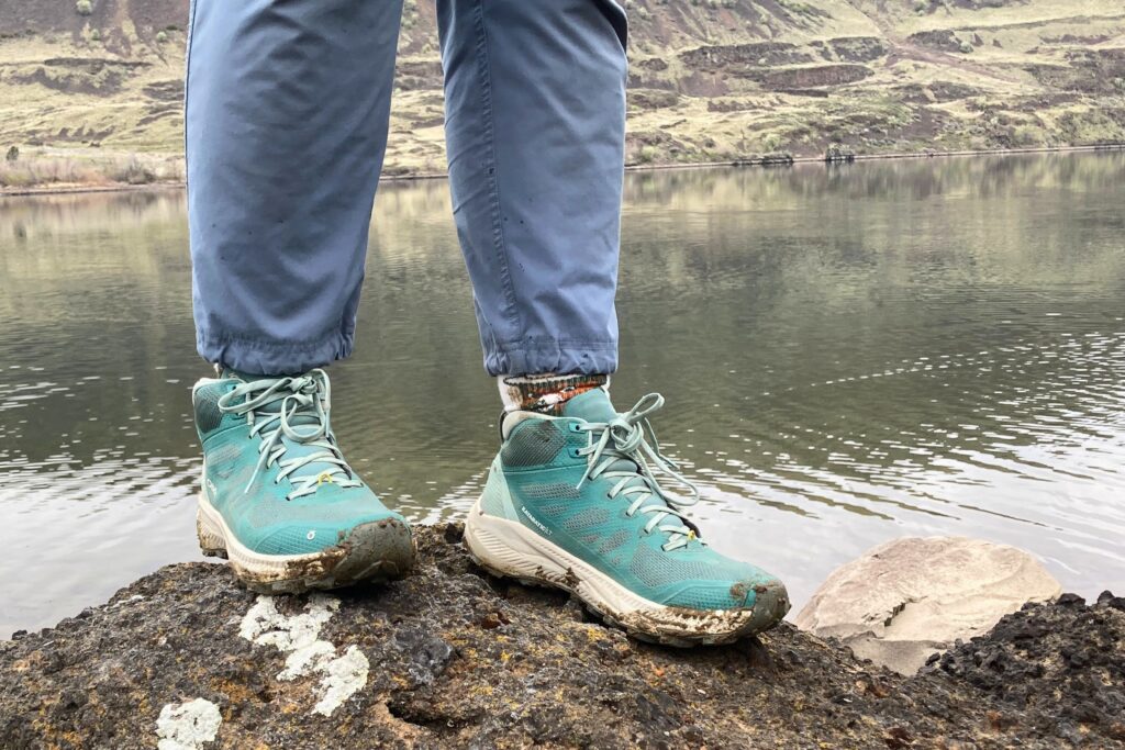 Hiker standing on a rock overlooking a river wearing the Oboz Katabatic LT Mid Gore-Tex Hiking Boots