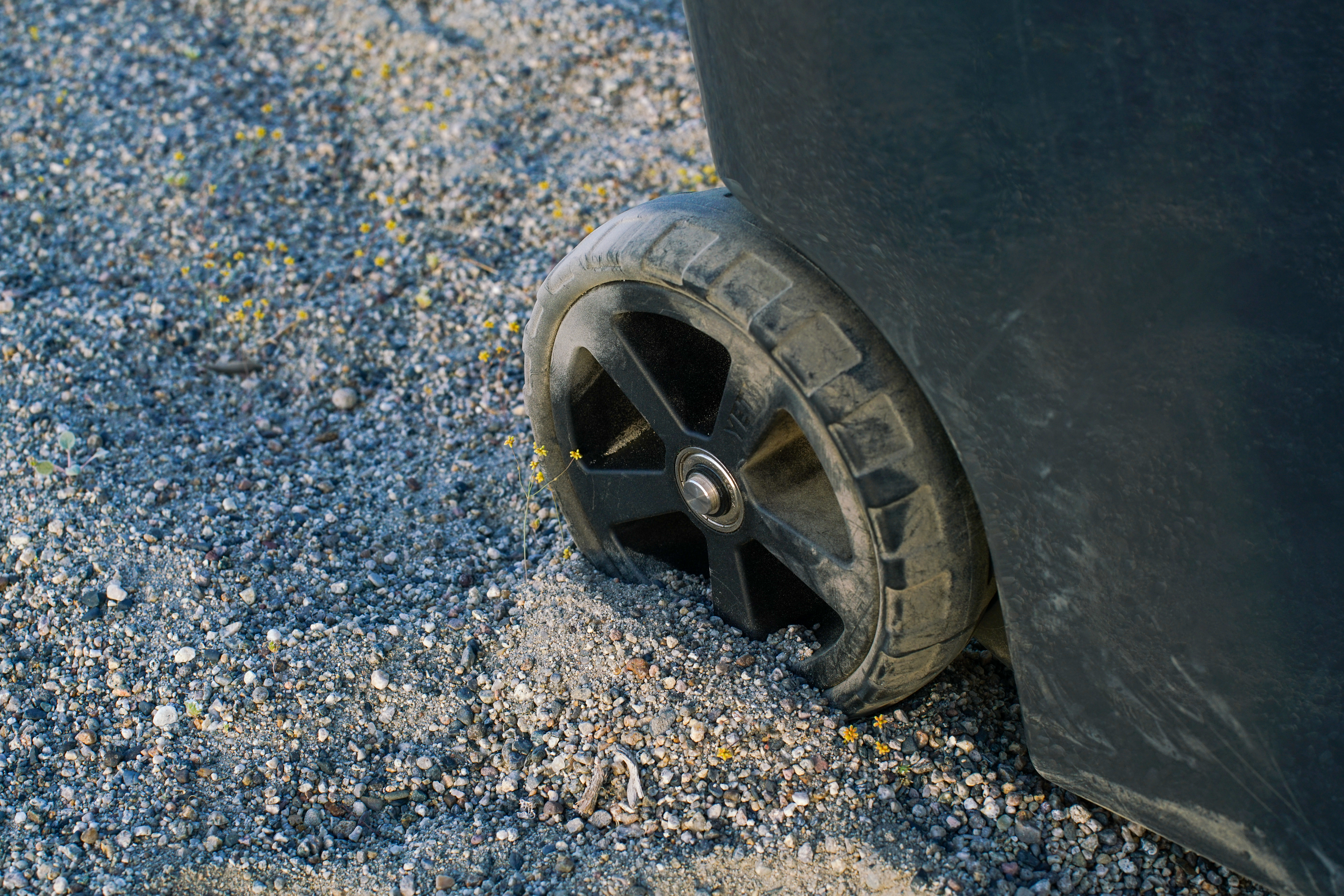 A close up of a single wheel on the YETI Roader 48 cooler. The wheel is partially submerged in sandy ground.
