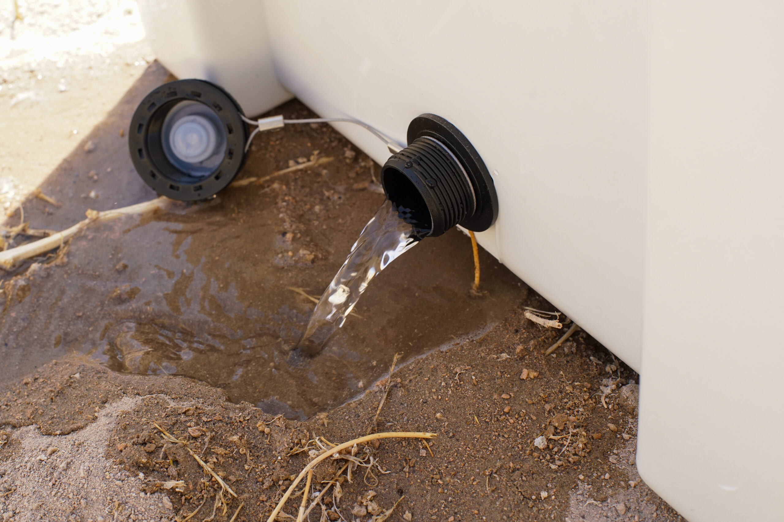 A close up of water pouring from the drainage hole in the side of the RTIC Ultralight 52 cooler.