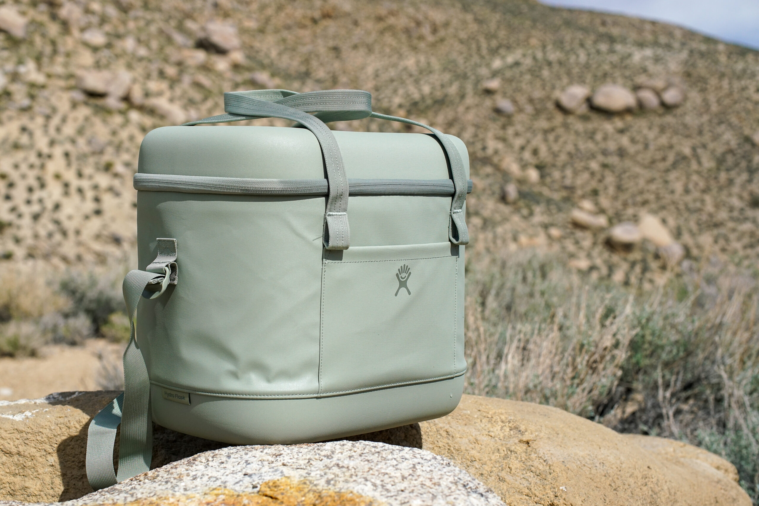 The Hydro Flask Carry Out 20L sits on a rock with boulders in the background.
