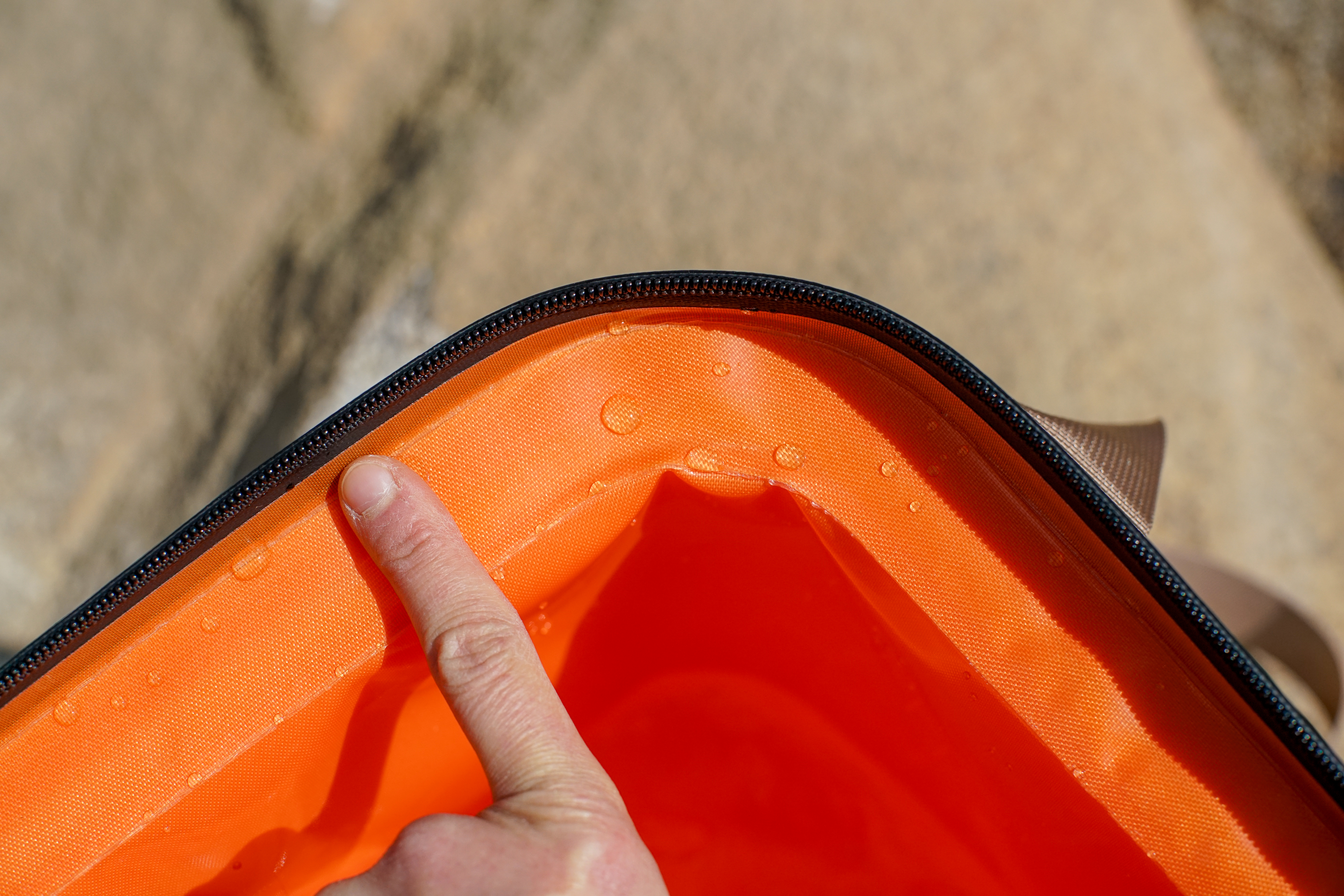 A close up of a corner of the RTIC Soft Pack cooler with a human finger providing scale for the cooler's layer of insulation.