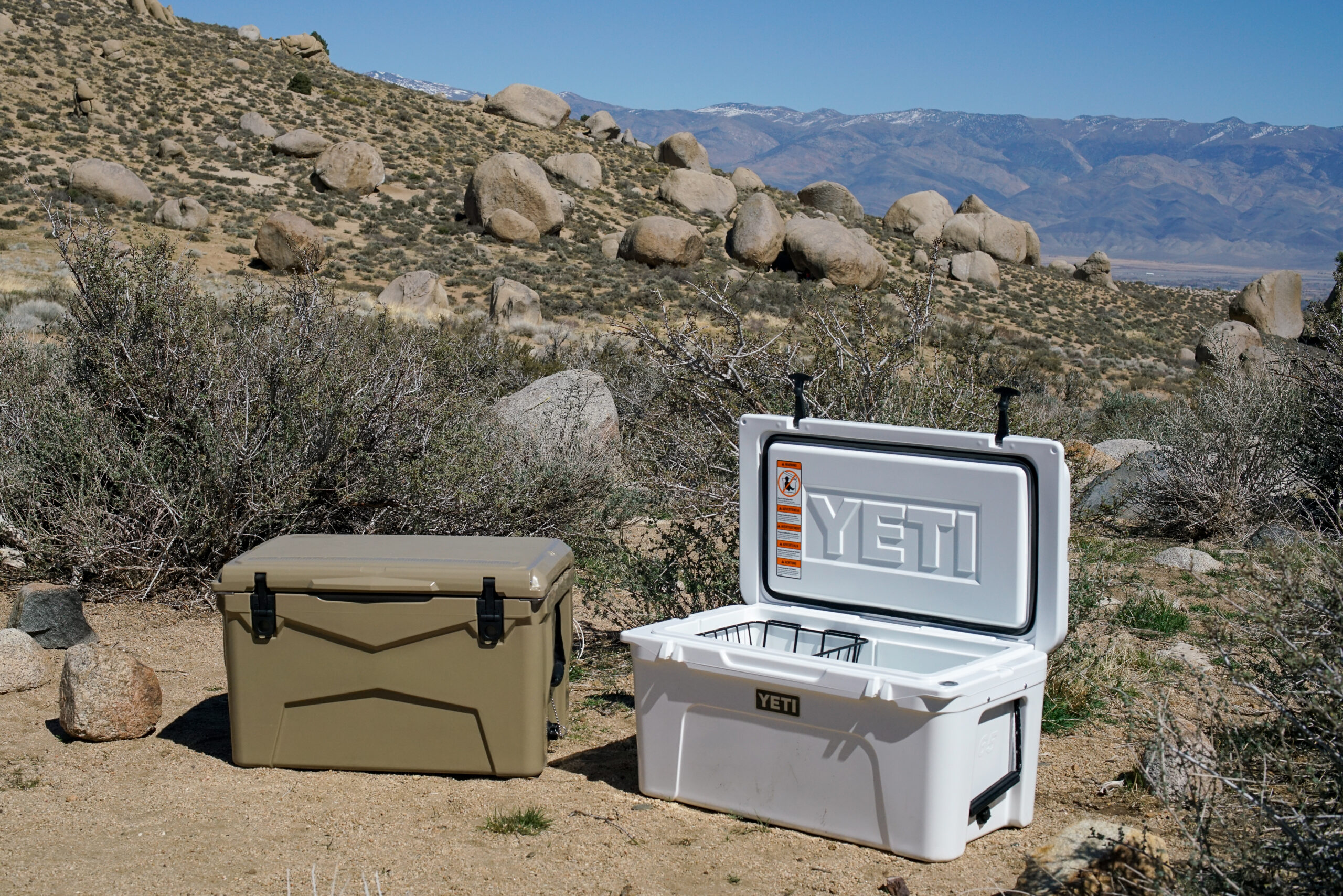The XSpec 60QT sits on the ground next an open YETI Tundra 65 cooler. There are boulders and mountains in the background.
