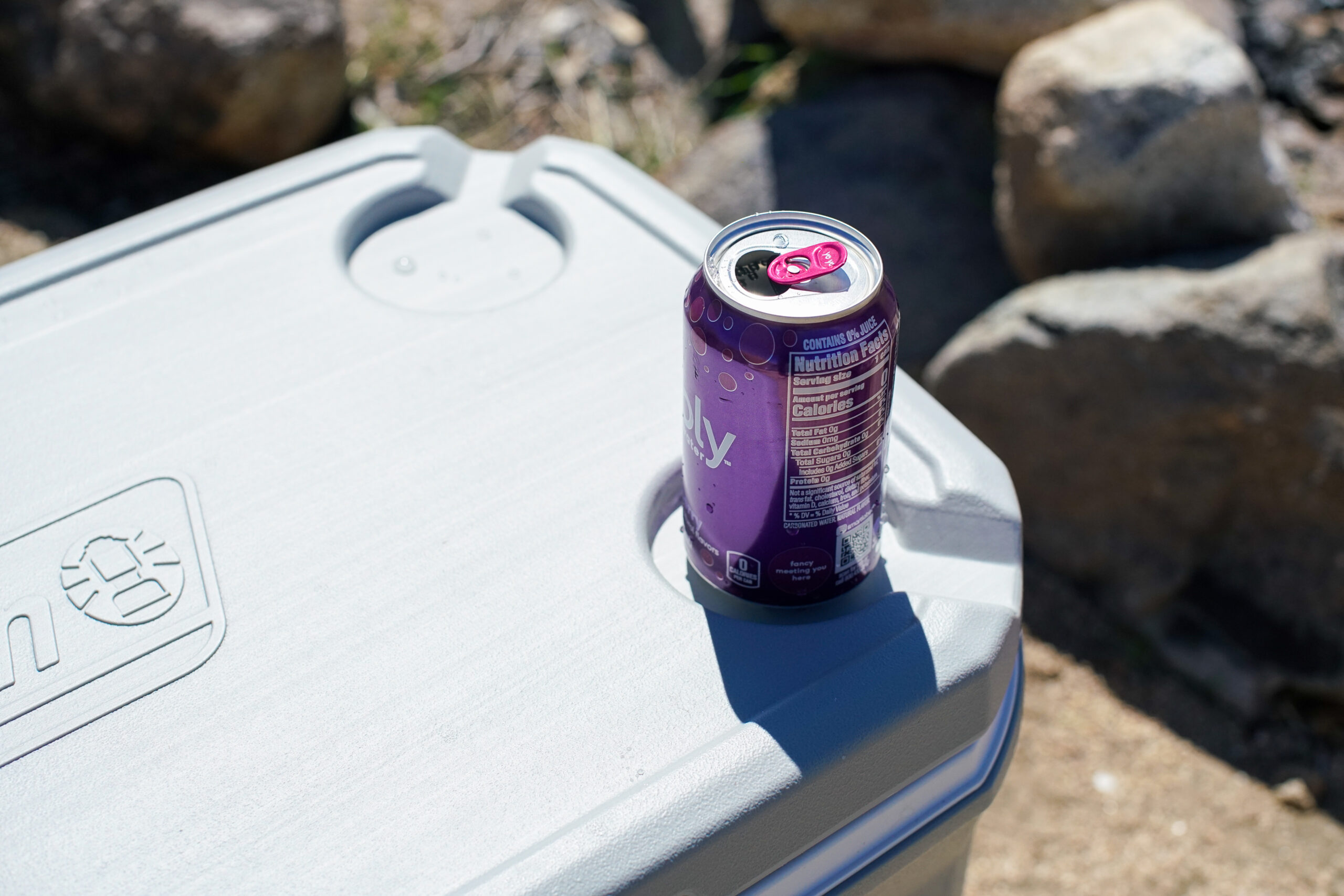 An open canned drink sits in the cupholder slot on the lid of the Coleman 316 Series 70QT cooler.