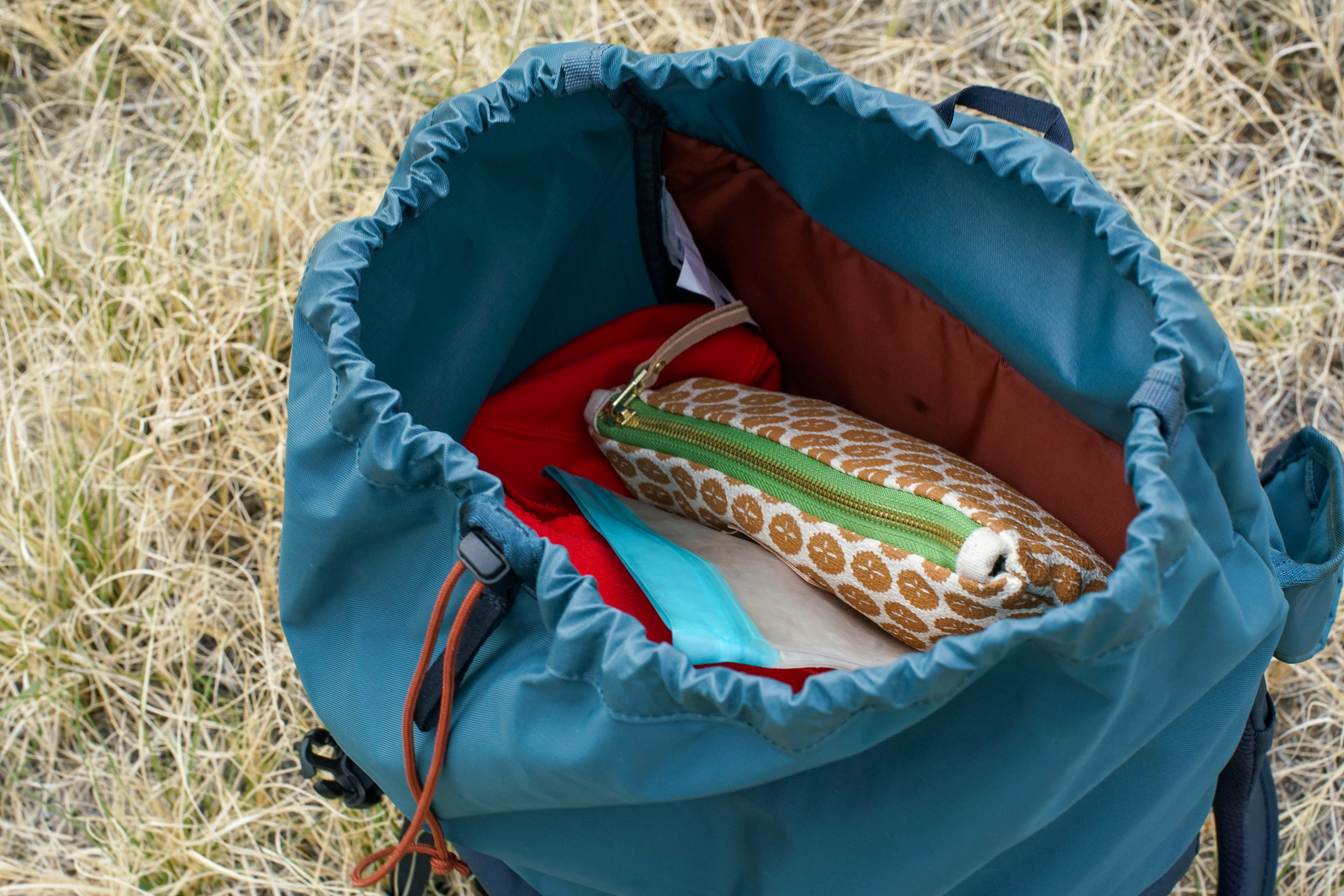 A close up of the open top half of the REI Cool Trail Split Pack. A plastic bag and zipper pouch are visible inside the compartment.