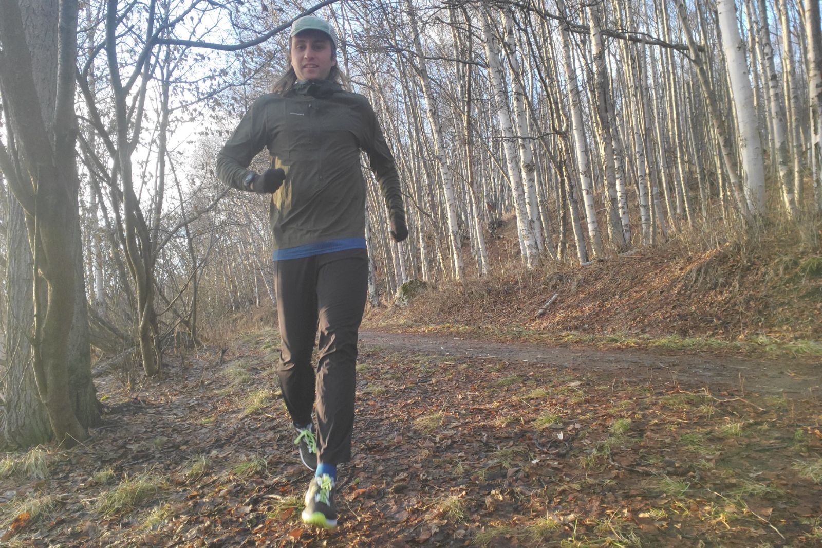 A man runs through a fall forest.