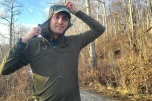 A man puts on the hood of a windbreaker.