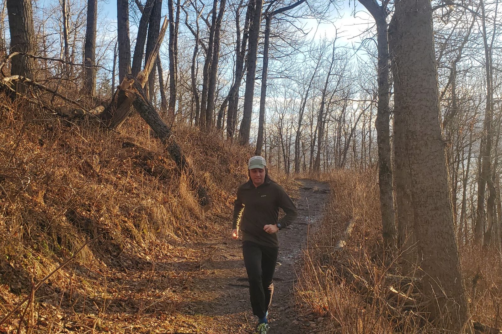 A man runs down a trail at sunset