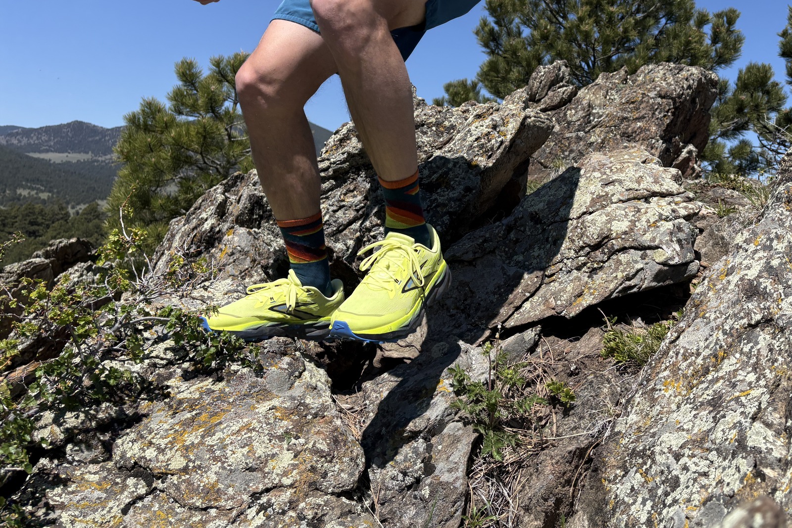 Legs down image of a person running on rocks in the mountains on a hiking trail.