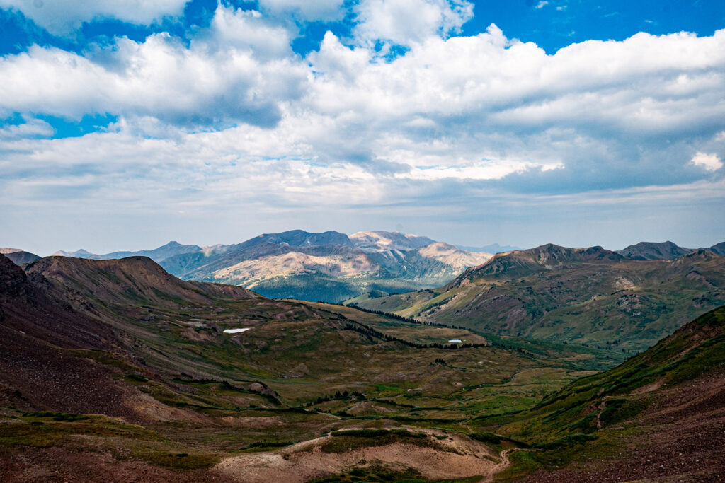 A wide open valley takes up most of the foreground with some mountain peaks in the distance.
