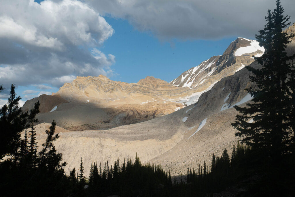 Late afternoon light glows on the side of a rocky mountain.
