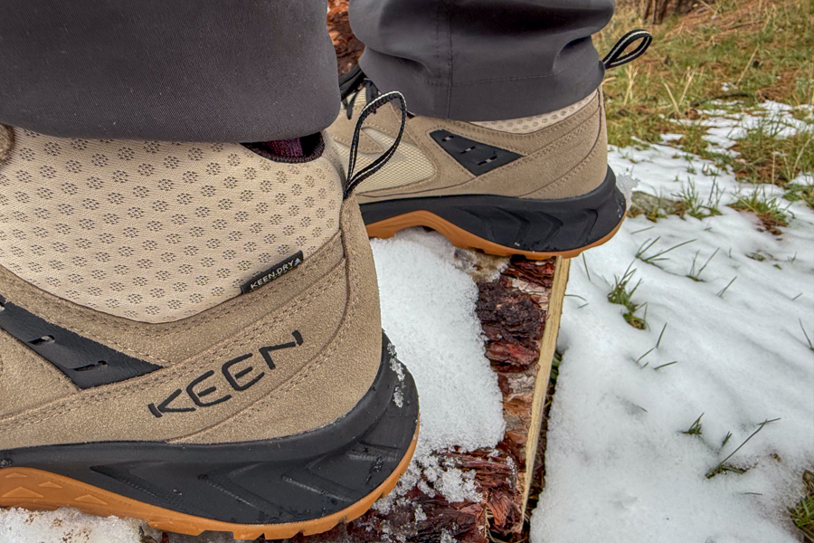Side view of Keen Hightrail Mid boot on a snow-dusted log, showing upper materials and midsole.