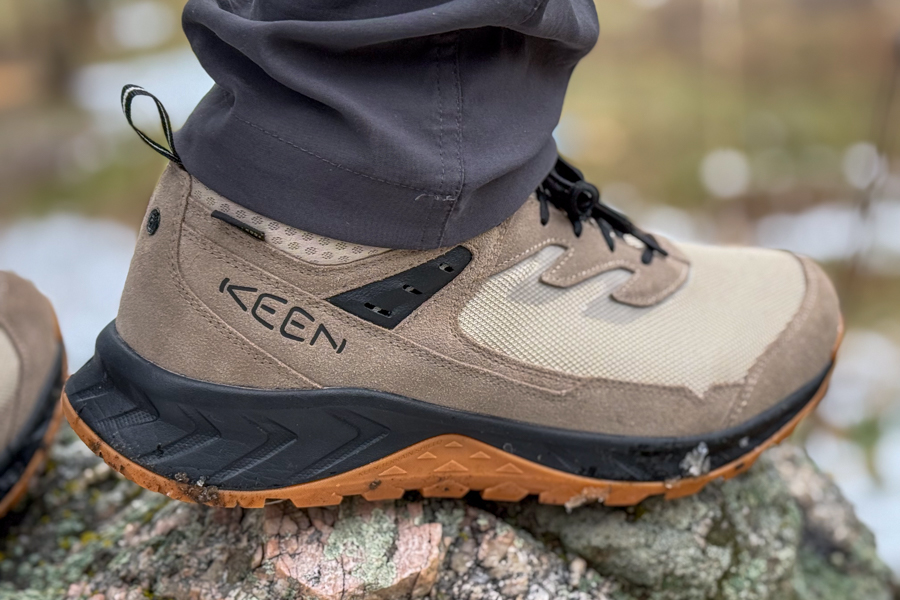 Hiker planting boots on Colorado granite mixed with snow and new spring growth.