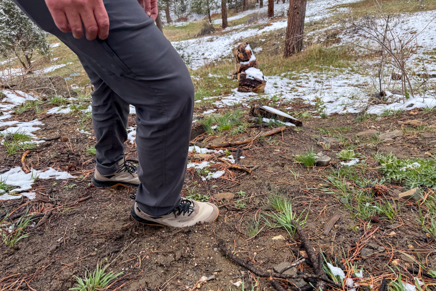 Wide shot of boots on mixed terrain—mud, snow, pine needles—showcasing boot performance.