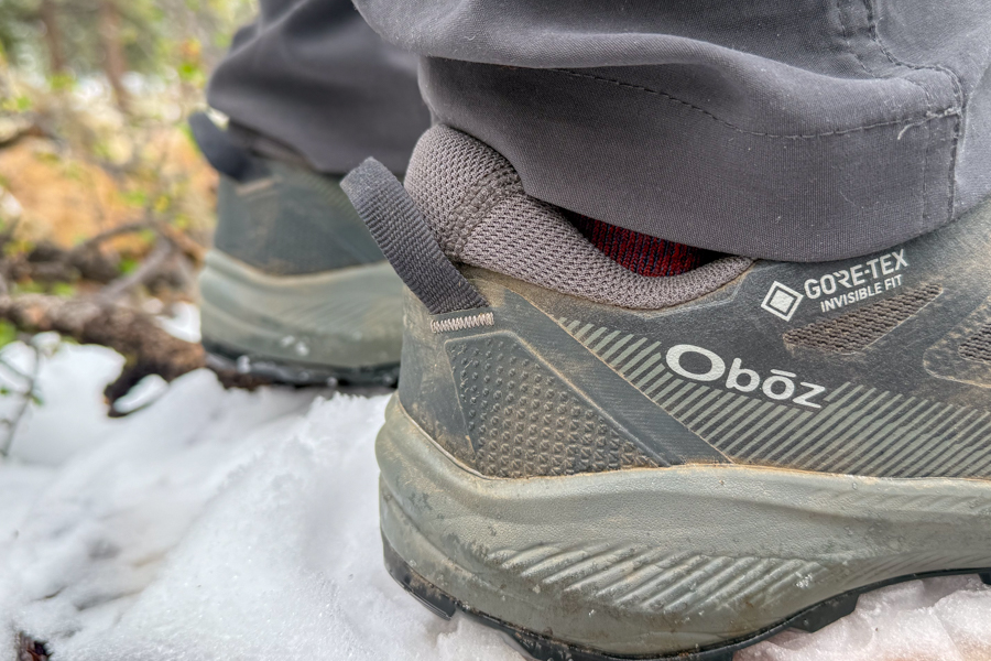 A closeup of a pair of hiking shoes in the snow. The image focuses on the heel of the shoes.