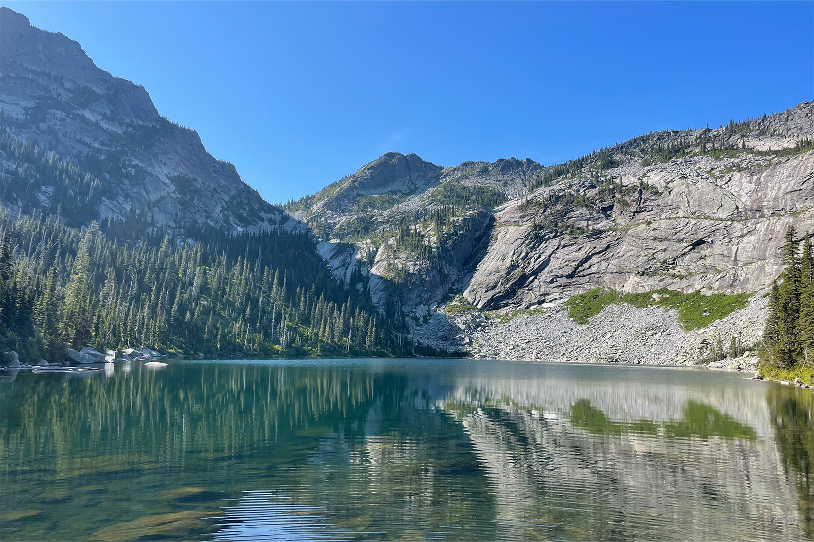 A blue lake is surrounded by granite peaks on a clear, sunny day.