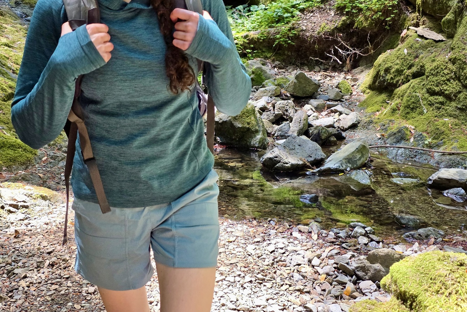 Woman hiking with a pack, focusing on a close up of her hiking shorts.