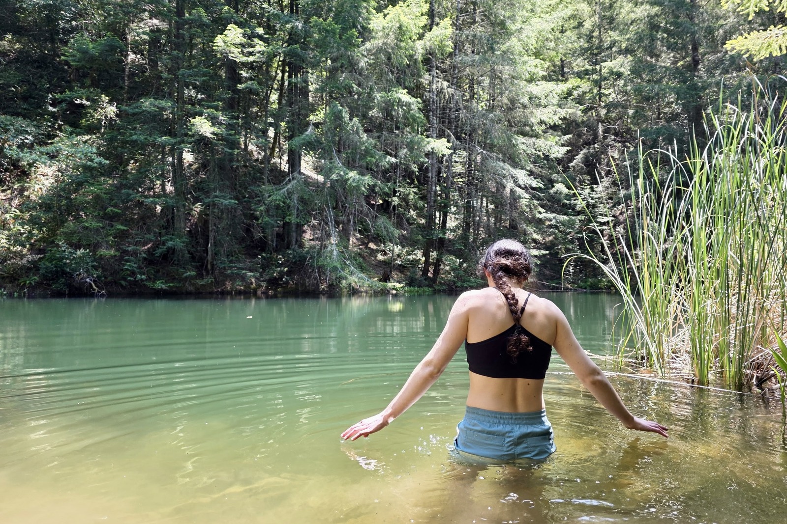 Woman wading in a lake to test the performance of hiking shorts when wet.