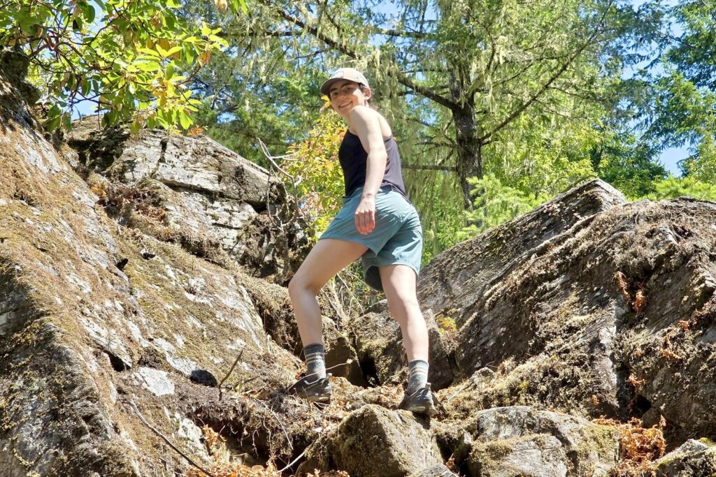 Women hikes in rocky and busy terrain in a pair of durable REI hiking shorts.