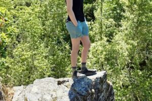Woman standing on a rock outcropping overlooking the scenery below.
