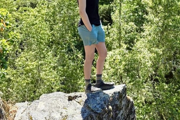 Woman standing on a rock outcropping overlooking the scenery below.