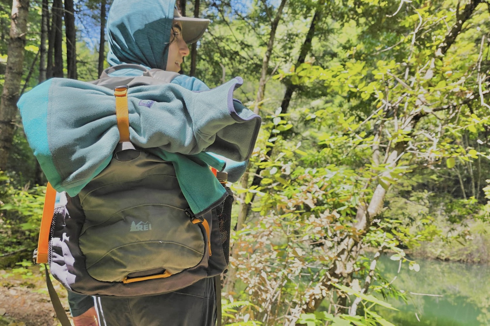 Woman is hiking with a fleece strapped to the outside of her backpack.