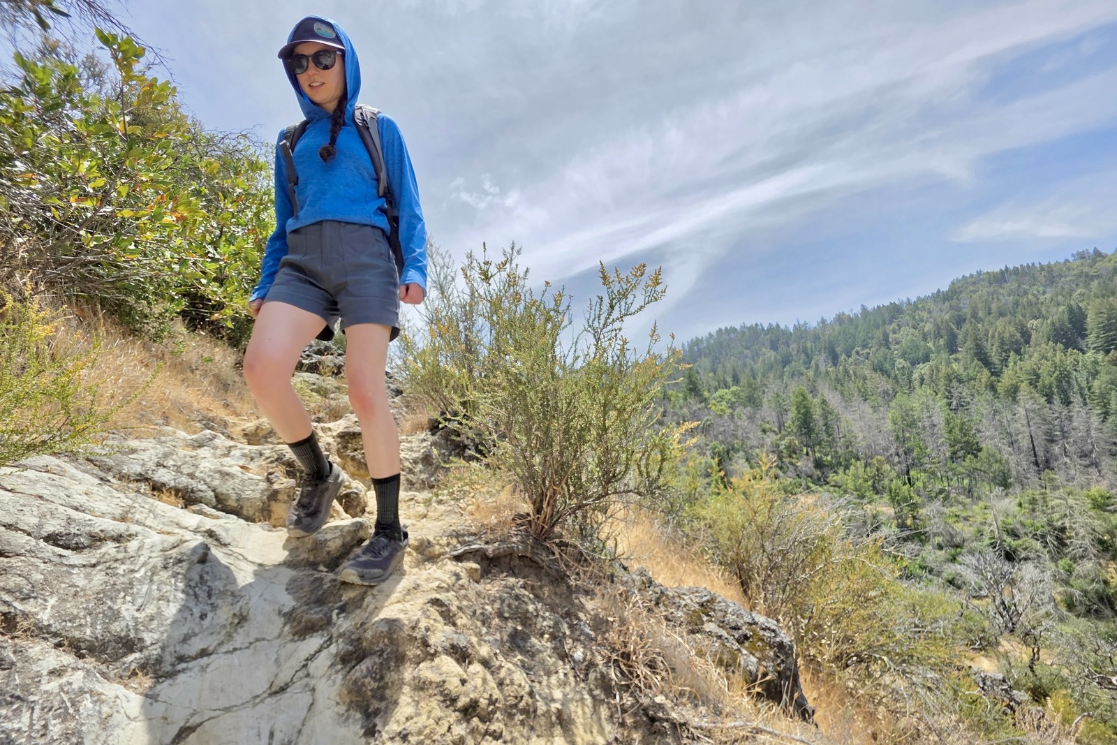 Woman hikes down a steep and exposed trail in Prana hiking shorts.