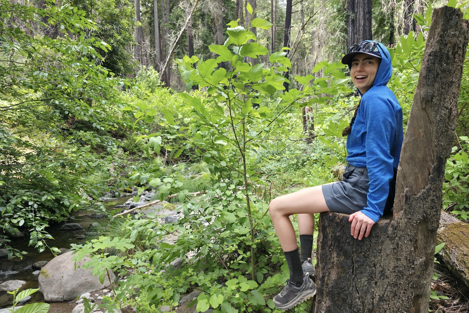 Woman sits on a tree stump that is shaped as a large chair.
