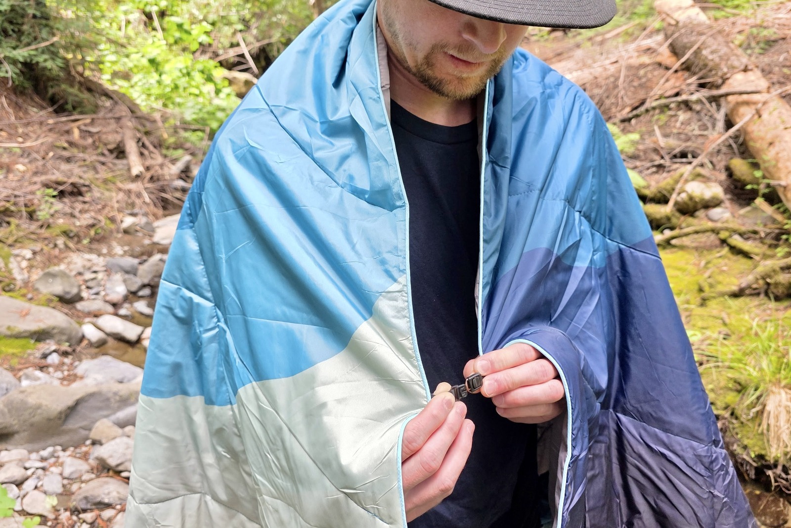 A man clips together a blanket around his shoulders using its cape clip feature.