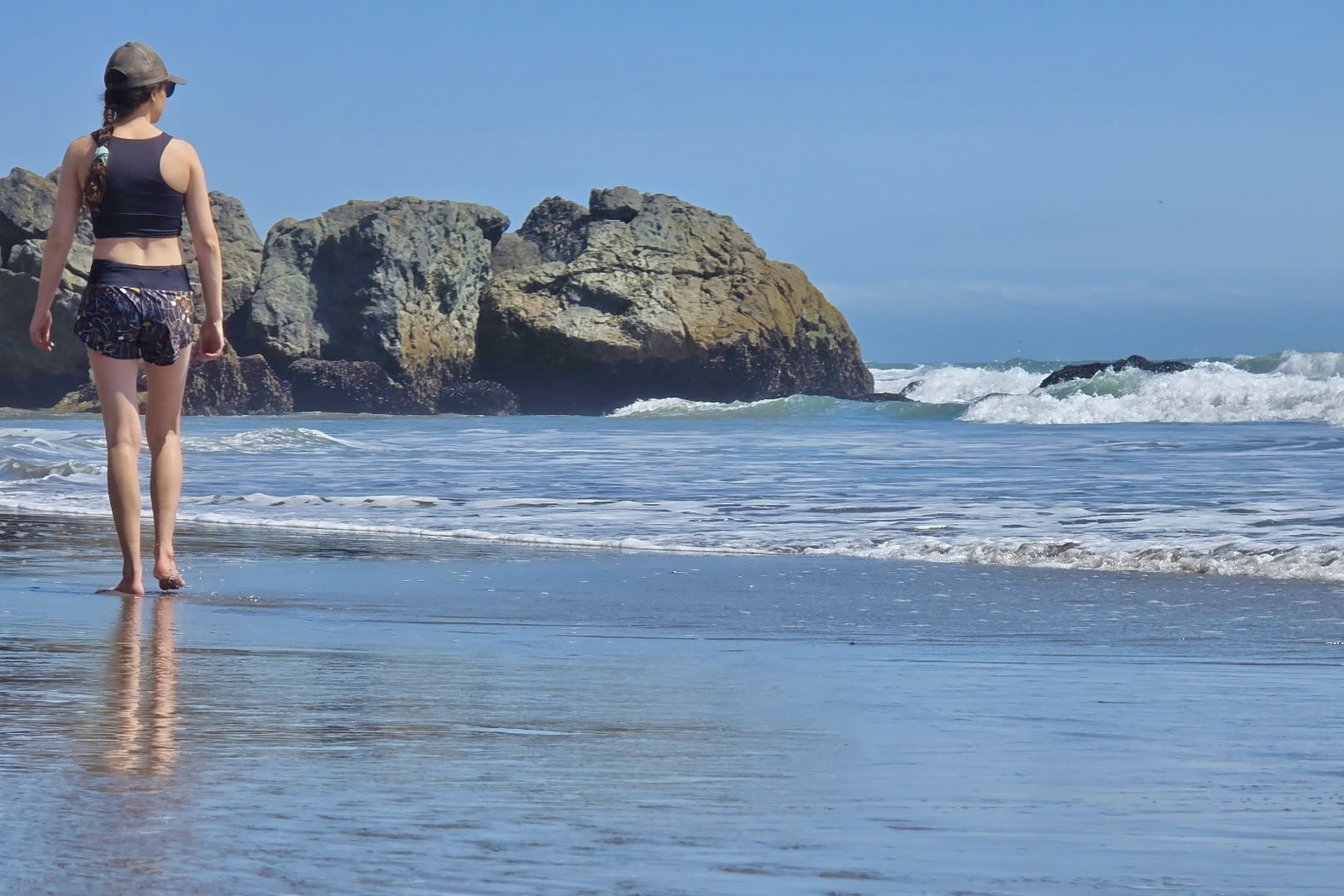 A woman walks along the beach in her Oiselle shorts.