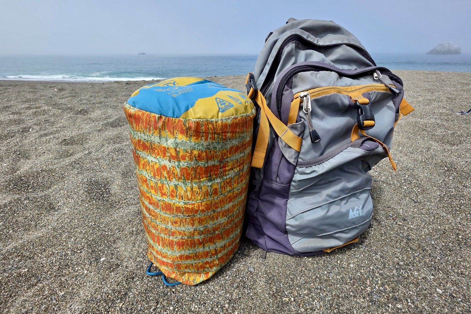 The Kelty Biggie rests against a daypack to compare its size.