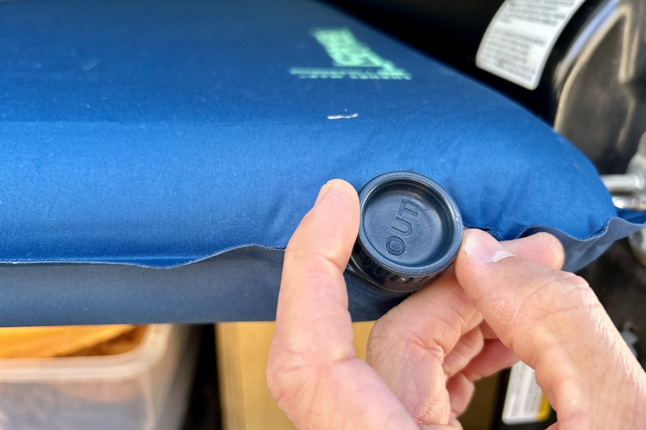 Close-up image of a person twisting a mattress air valve closed.