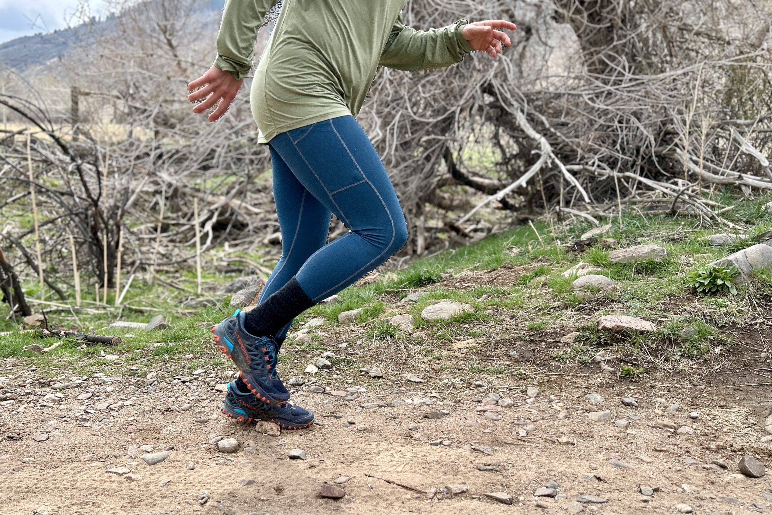 Side-profile view of a man from the waist down, running on a trail.