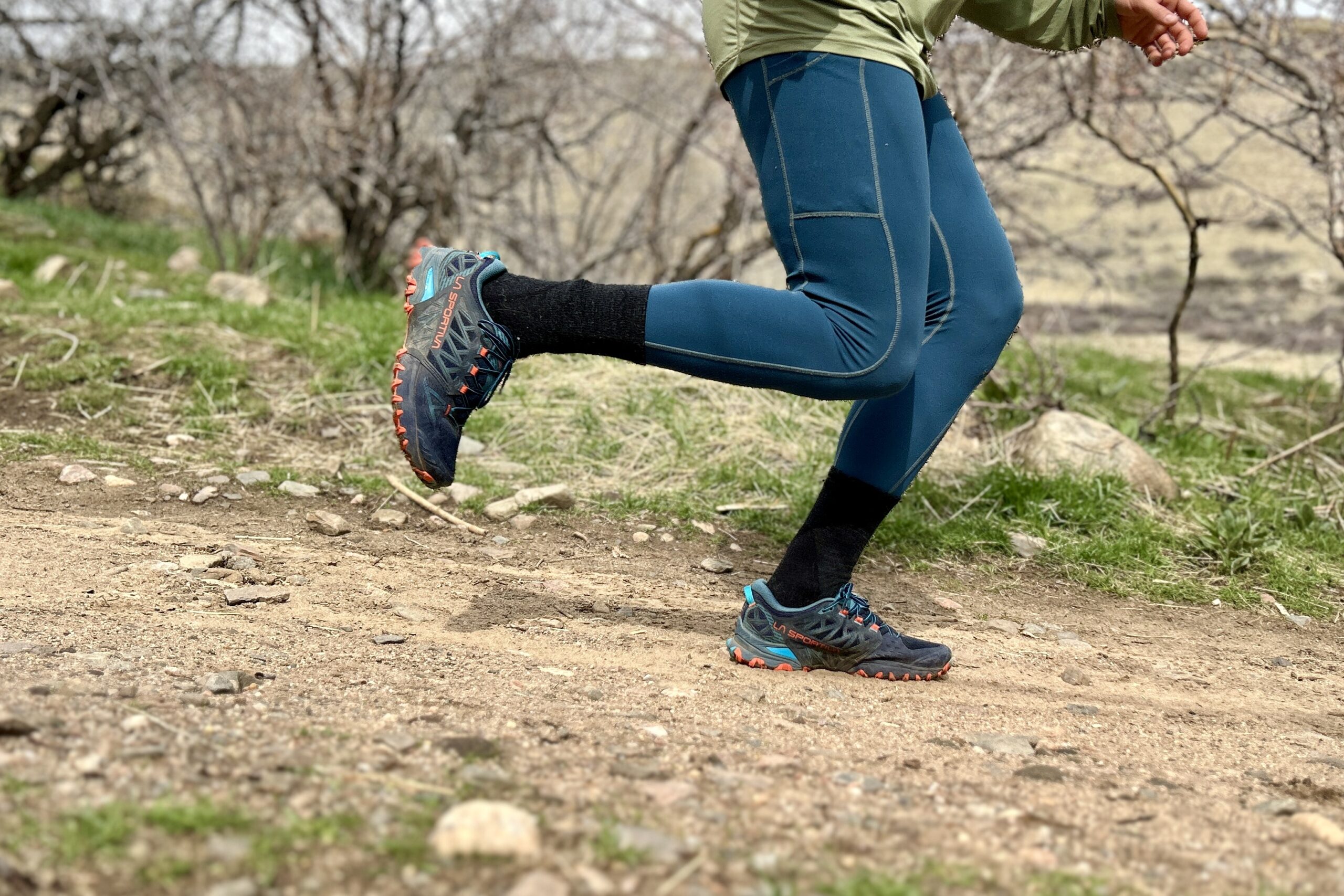 Side-profile view of a man from the waist down, running on a trail.