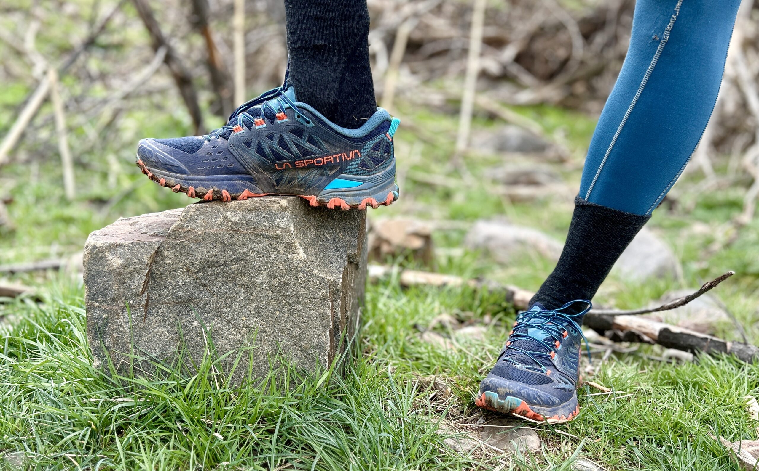 Image of a person from the knees down wearing leggings and trail runners while posing on a rock.