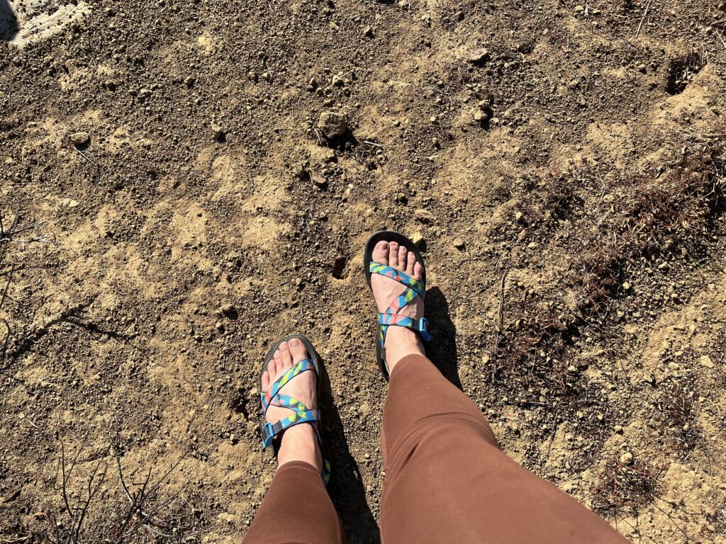 A woman walking along a dirt trail wearing Chaco Z/1 Classic hiking sandals.