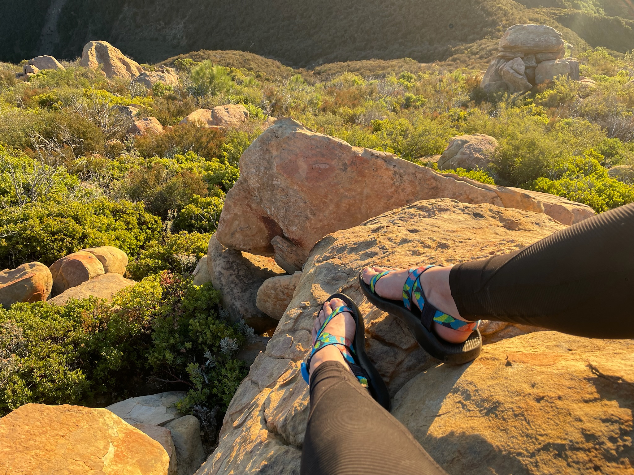 A woman's feet in Chaco Z/1 Classic hiking sandals in a rocky, mountainous environment.