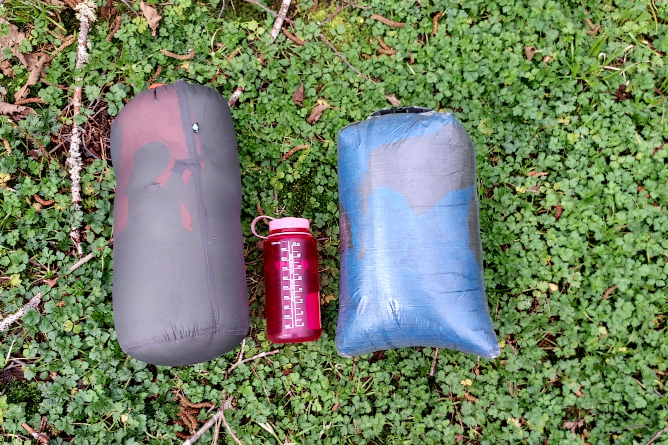 The Enlightened Equipment Accomplice and ZPacks 20F (-7C) Twin Quilt in stuff sacks with a Nalgene for scale