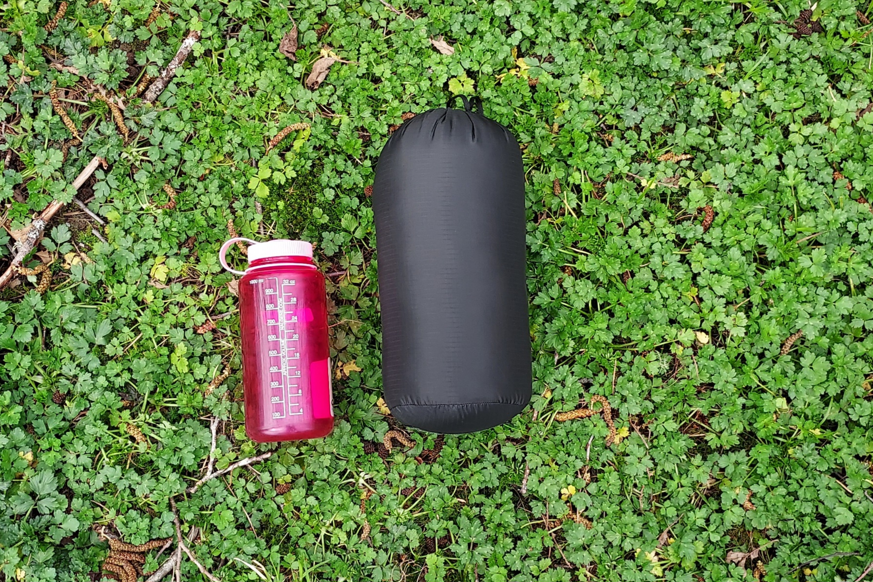 The Western Mountaineering AstraLite Quilt packed down with a Nalgene for scale