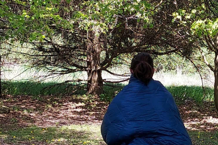 Hiker wearing the Loco Libre Operator Series Ghost Pepper 20 Quilt in camp