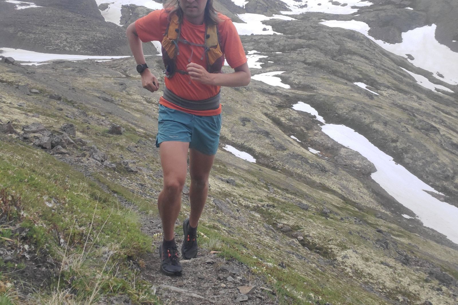 A man runs up an alpine trail.