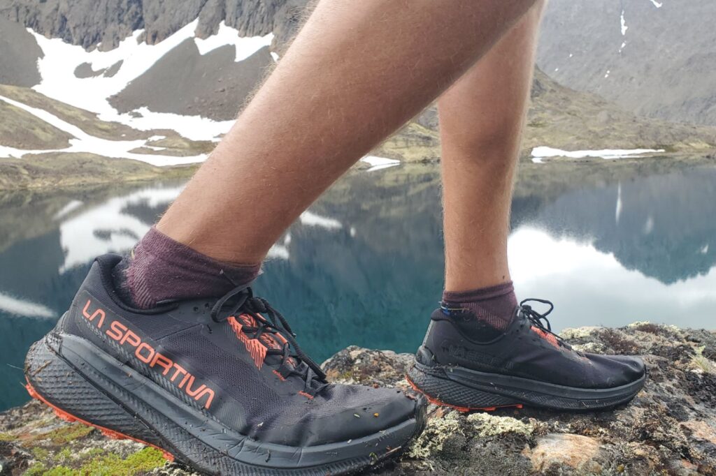 A closeup of shoes above an alpine lake.