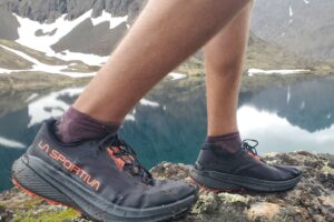 A closeup of shoes above an alpine lake.