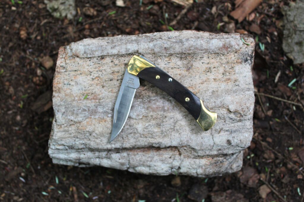 The Buck Knives 055 Pocket Knife halfway open on a rock